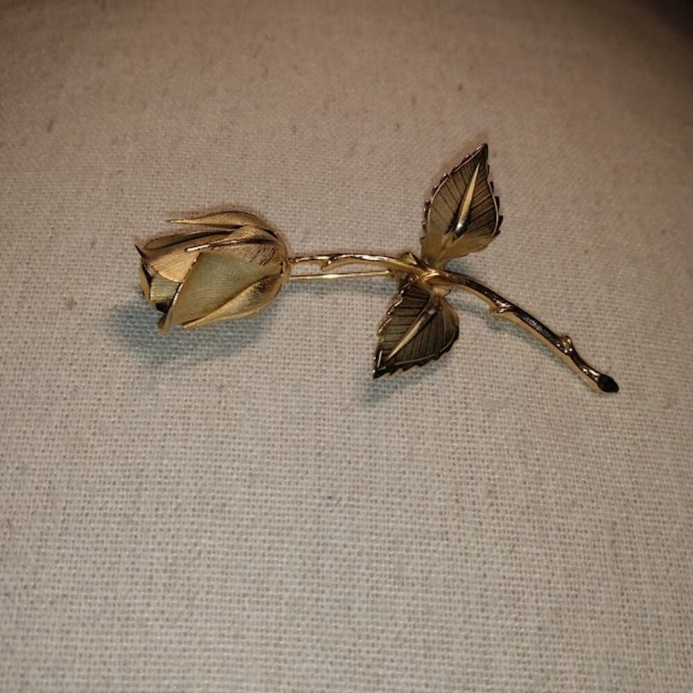 Giovanie: Gold tone single stem rose brooch.